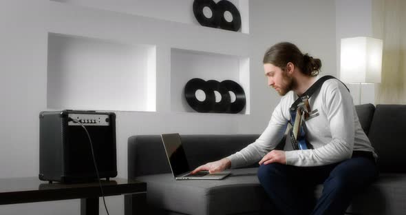 Caucasian Young Man Watching Online Video Lesson on Playing the Guitar