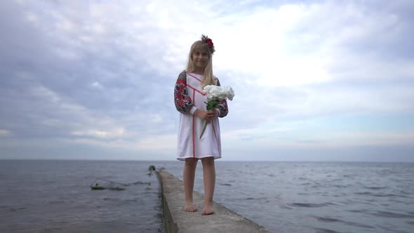 Wide Shot Happy Little Ukrainian Girl in Traditional Embroidered Clothing Standing on River Pier