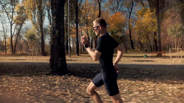 Running Man In Forest At Sunset. Runner Man Fit Athlete Legs Jogging On Trail Ready To Triathlon.