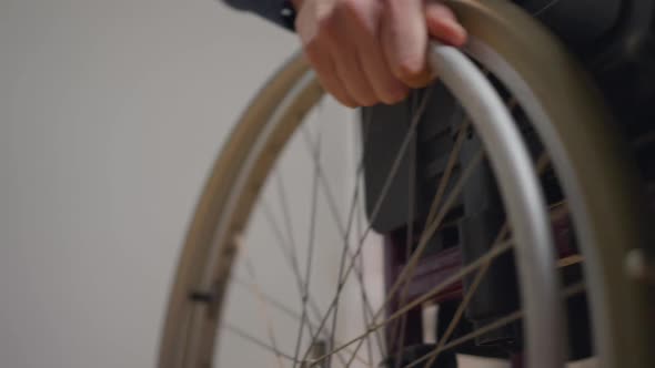 Closeup Male Young Hand Rolling Wheel of Wheelchair Rolling Away