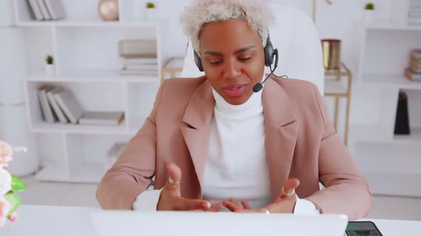 Smiling Young African American Woman Wear Headset Talking By Web Call in Office