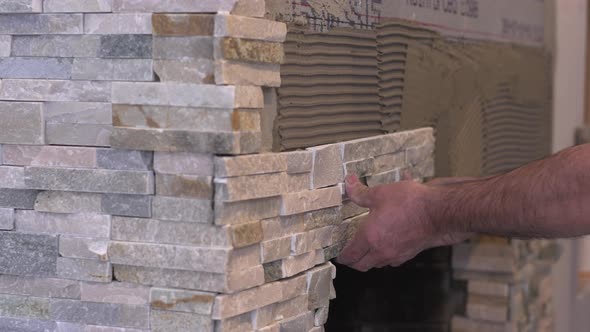 Male Worker Hands Setting Stacked Stone Tiles for Fireplace