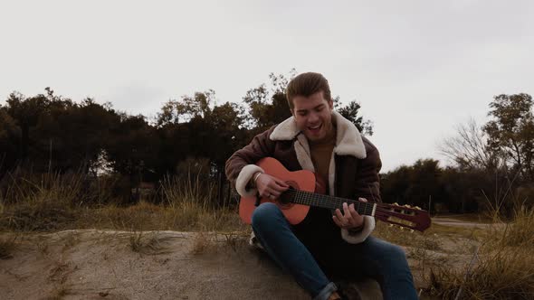 young boy smiles while playing the guitar