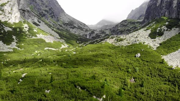 AERIAL: Revealing two Foggy Mountains near Pine Forest in Slovakia High Tatras Region