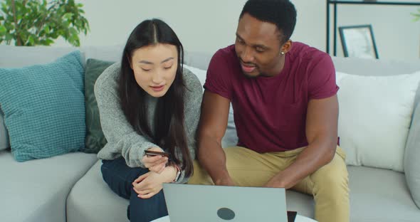 Happy Mixed Ethnicity Young Couple Using Laptop for Ecommerce Doing Online Shopping