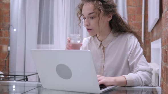 Portrait of Young Female Drinking Coffee and Working on Laptop