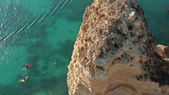 People in Canoes Rowing in Ocean at Rock Coastline of Ponta De Piedade Portuga