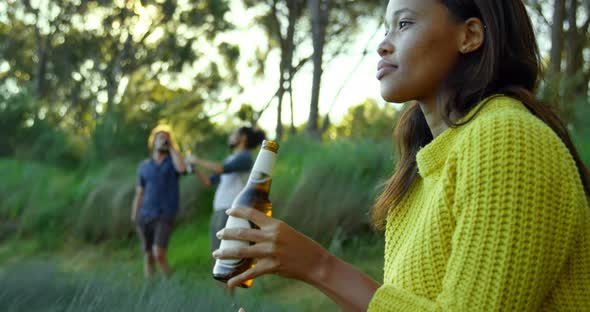 Thoughtful young woman drinking beer in the forest 4k