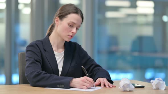 Young Businesswoman Trying to Write on Paper in Office