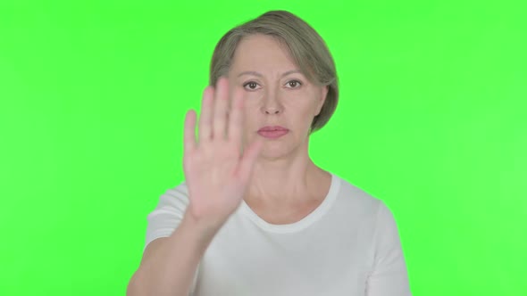 Stop Gesture By Old Woman in Denial on Green Background