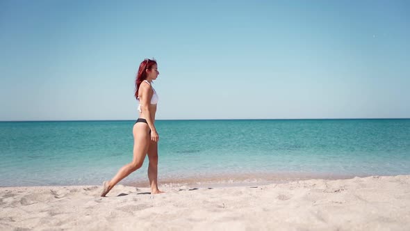 Beautiful Girl in Swimsuit Walking Along Transparent Turquoise Sea Along Coast