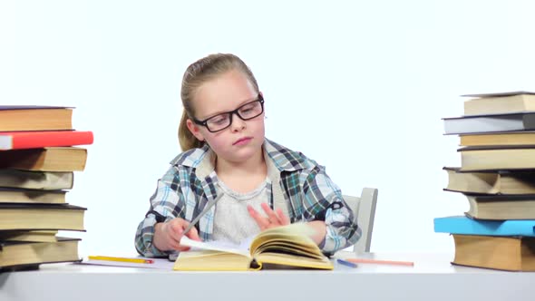 Girl Sits at the Table Leafing Through the Book. White Background