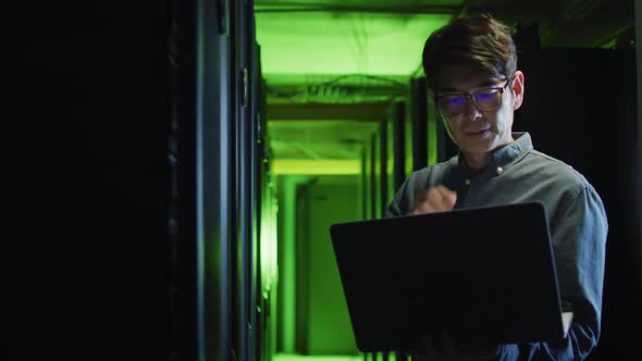 Asian male it technician using laptop checking computer server