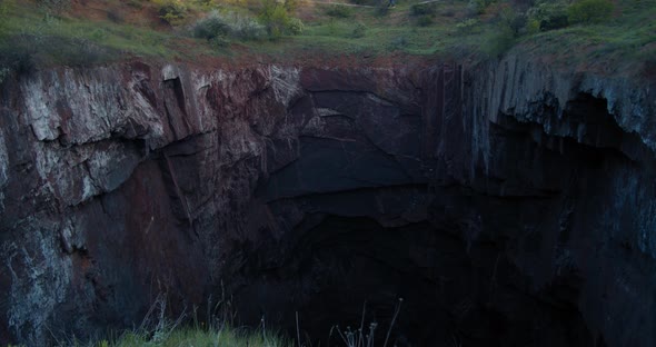 Huge Natural Pit with a Man Balancing on the Slackline Over It