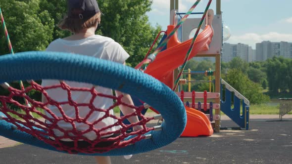 Slow Motion of Young Caucasian Woman Swinging on Big Blue Wicker Nest Swing