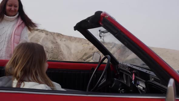 Mom Get Into Red Vintage Convertible Car with Young Daughter