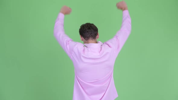 Rear View of Happy Young Businessman with Fists Raised