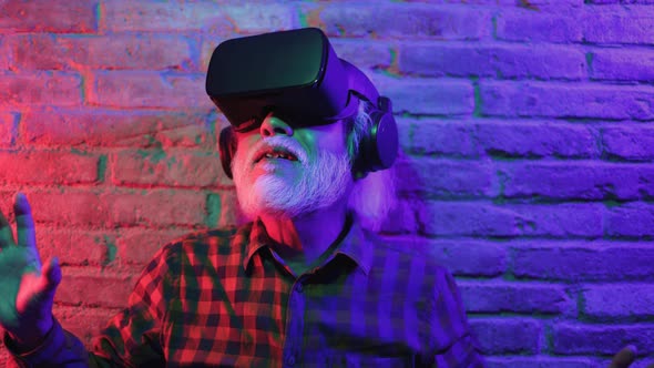 Metaverse virtual reality concept - Asian senior man having fun wearing VR goggles