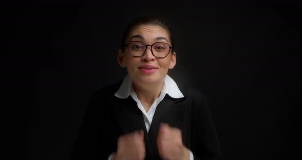 Asian Woman Stands on an Black Background and Looks Pleadingly Into the Camera