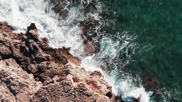 Rocky Seashore Hit by White Extreme Waves Splashing and Creating White Foam