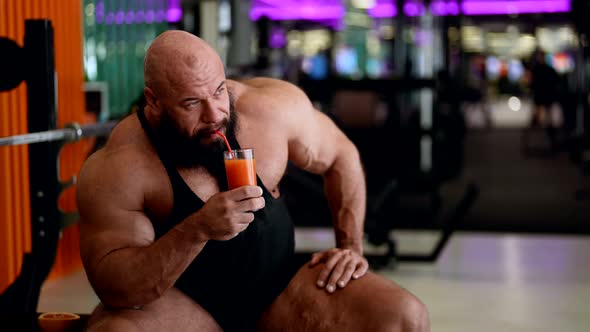 Sporty Man with Large Muscles is Resting in Gym and Drinking Vitamin Juice Cocktail Powerlifter