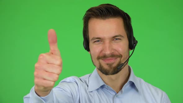 A Young Call Center Agent Shows a Thumb Up To the Camera and Smiles - Closeup - Green Screen Studio