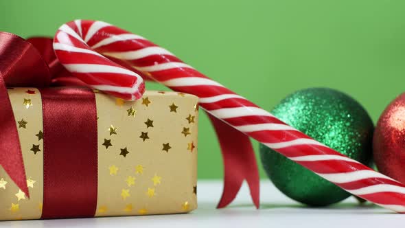 A Christmas gift arrangement with a red bow, Christmas tree balls, and a caramel cane.