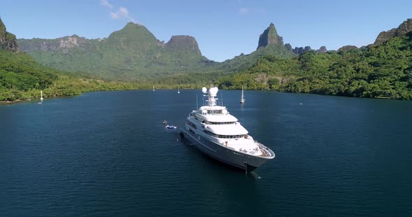 Aerial views of yacht in French Polynesia, stunning backdrop with large mountain in background