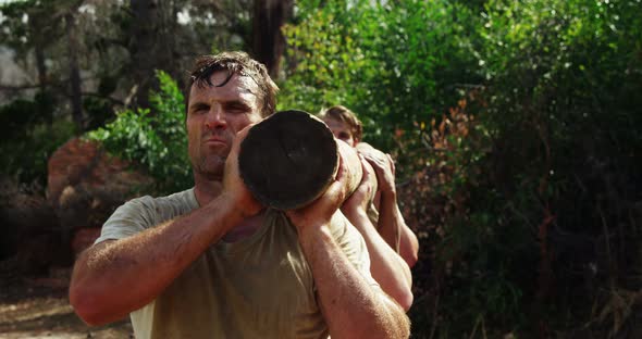 Military troops carrying heavy wooden log during obstacle course