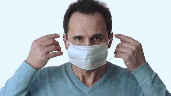 Man Puts on Medical Mask Against Pandemic Covid-19. Isolated on White Background