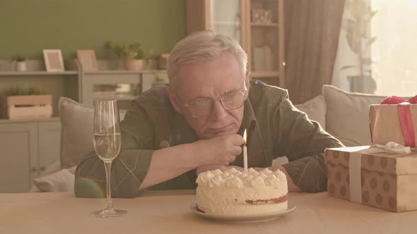 Sad Senior Man Looking at Birthday Cake