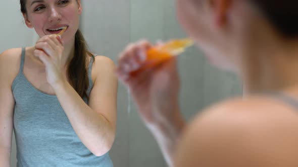 Pretty Woman Brushing Her Teeth in a Bathroom in the Morning