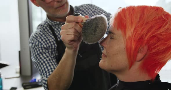 Front view hairdresser cleaning the face of a woman