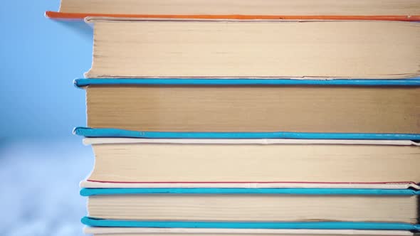 stack of old books are piled on an old wooden table. 