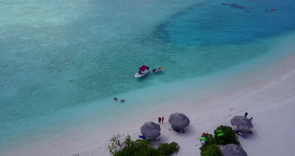 Daytime fly over island view of a sunshine white sandy paradise beach and blue ocean background in c