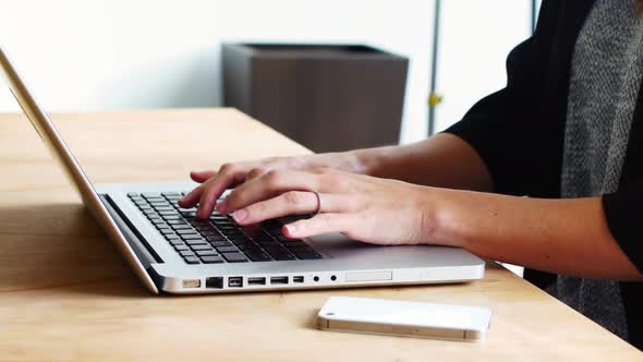 Mid section of female executive sitting at desk and using laptop