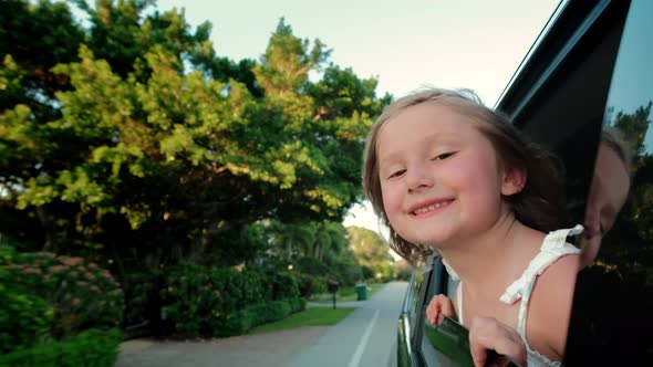 Teen Girl Ooking Out the Car Window and Waving His Hand