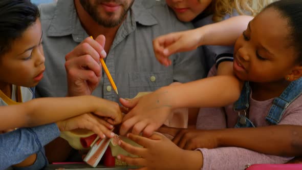 Diverse group of school children studying anatomy in classroom with teacher at desk 4k