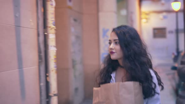 Beautiful Spanish Woman With Paper Bag Arrives At Condo Unit Press On Video Intercom On The Wall