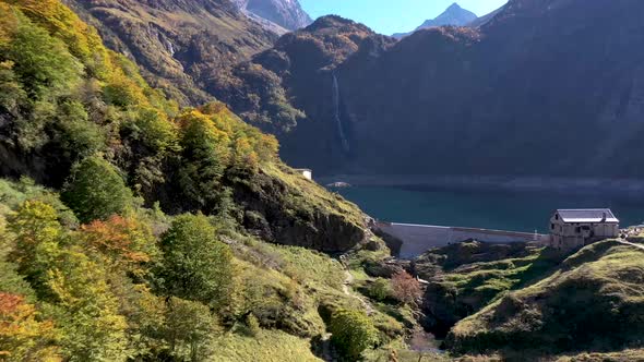 Lac d'Oô artificial lake in the French Pyrenees with hikers standing near the dam wall on a ridge, A