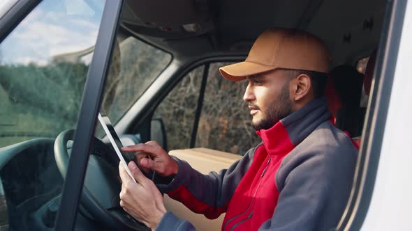 Courir Looking at Tablet and Then Outside to Confirm Delivery Address