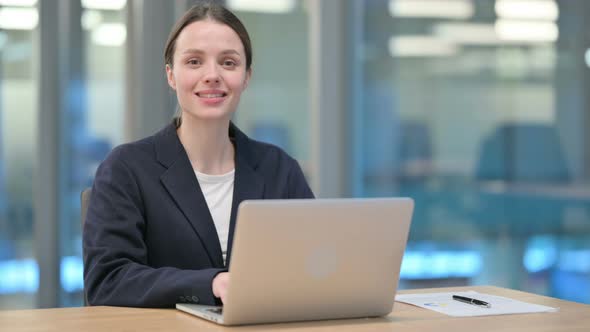 Young Businesswoman Smiling at Camera while working on Laptop