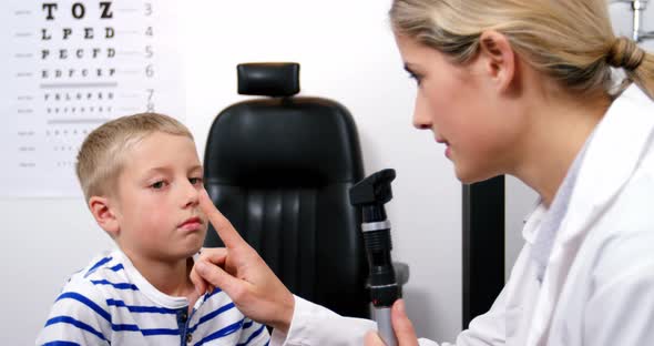 Female optometrist examining young patient with ophthalmoscope