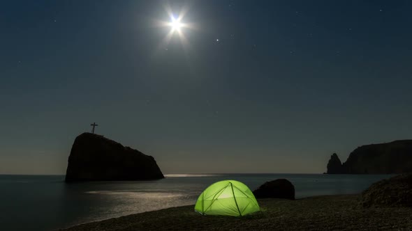 Green tent on the beach at night under the starry sky.