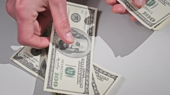 Male Hands Counting Old Hundred Dollar Banknotes on a White Table