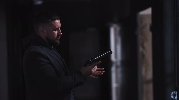 Adult Man Holding a Gun in His Hands and Puts the Magazine in the Gun