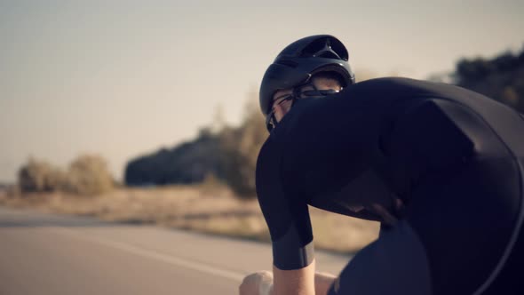 Cyclist In Helmet Riding On Time Trial Bicycle At Sunset.Triathlete Training Endurance Cycling Race.