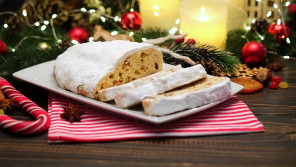 Sliced Traditional Christmas Stollen Cake with Marzipan and New Year Decorations on Wooden