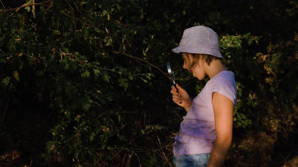 Naturalist Children Girl with Loupe Studying Learning Nature Outside and Makes Notes in Notebook