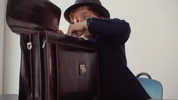 Portrait of Boy Boss Takes a Pack of Hundreddollar Banknotes Out of His Briefcase